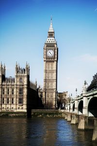 Big ben by thames river against clear sky in city