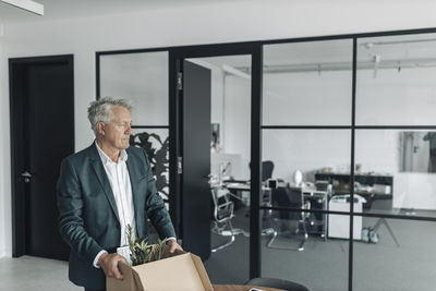 Businessman holding box while standing at office