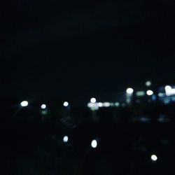 Defocused image of illuminated lights against sky at night