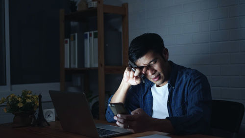 Young man using mobile phone while sitting on table