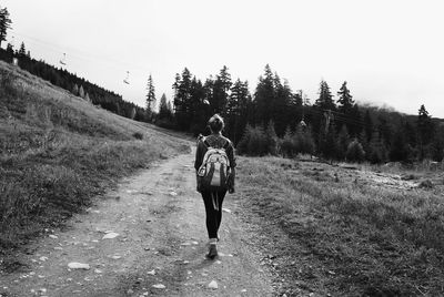 Rear view of woman walking on road against clear sky