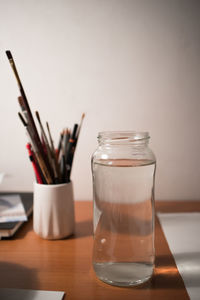 Close-up of water in jar on table against wall