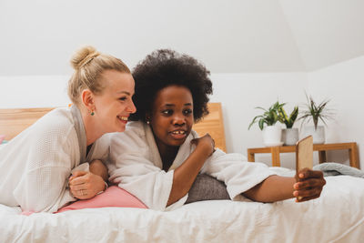 Portrait of young woman sitting on bed at home