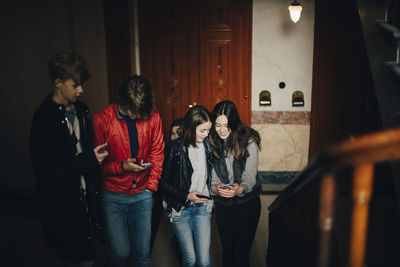 High angle view of male and female friends using mobile phone while walking up on steps