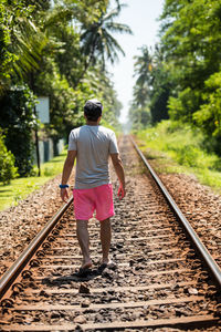 Rear view of man walking on railroad track