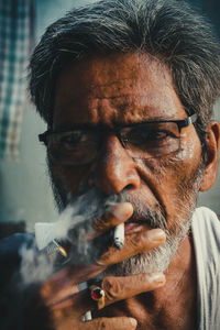 Close-up of man wearing eyeglasses smoking cigarette