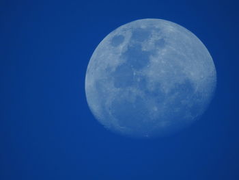 Low angle view of moon against clear blue sky