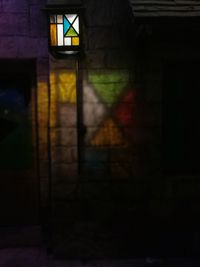 Illuminated building by wall at night
