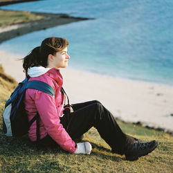 Side view of young woman sitting on beach