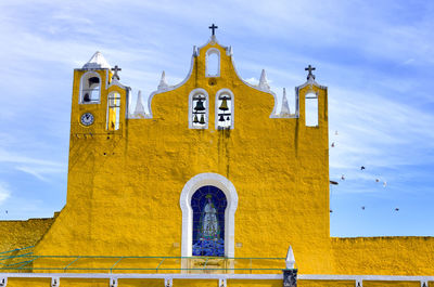Low angle view of yellow church against blue sky