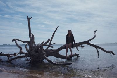 Low angle view of young woman jumping on beach against sky