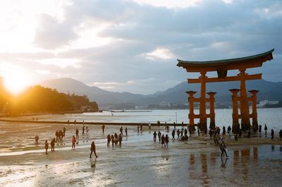 People on beach against cloudy sky