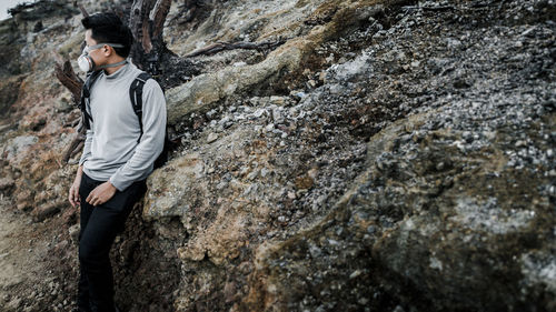 Man wearing pollution mask while standing against rock formation