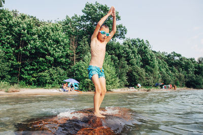 Full length of shirtless man jumping in water