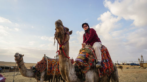 Chinese asian woman tourist riding camel giza pyramid tour destination of egypt