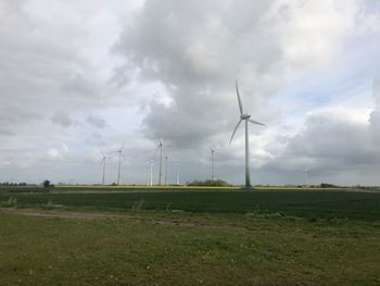 Windmills on field against sky