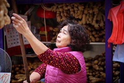 Female vendor holding stick while looking up at market