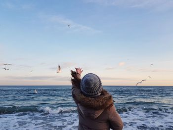 Rear view of girl looking at sea against sky