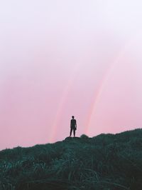 Man standing on field against sky during sunset