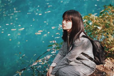 Young woman sitting by lake