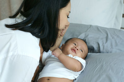 Mother with baby boy on bed at home