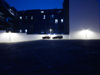 Car on illuminated street against buildings at night