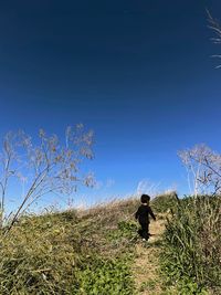 Man standing on field against clear blue sky