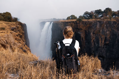 Rear view of woman sitting on land against sky