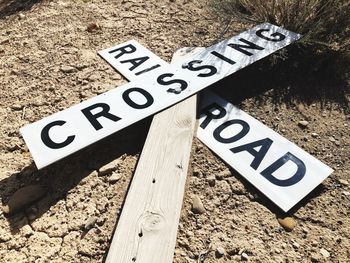 Fallen railroad crossing sign on land during sunny day