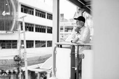 Man looking away while standing by railing