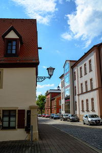 Residential buildings by street against sky