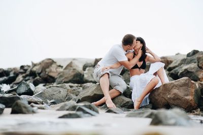 Couple kissing at beach against sky