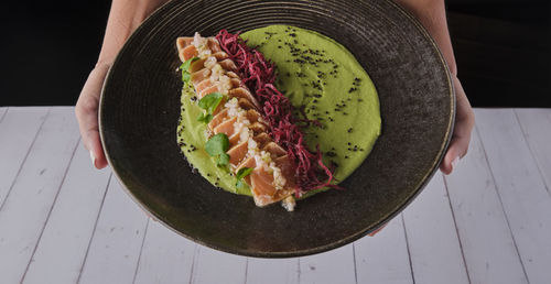 Close-up of savory japanese salmon tataki dish topped with sesame and served with crispy strips. 