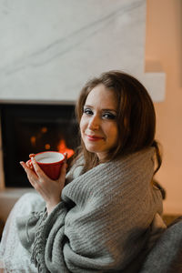 Portrait of smiling young woman drinking coffee