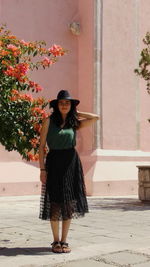 Portrait of smiling young woman standing against wall