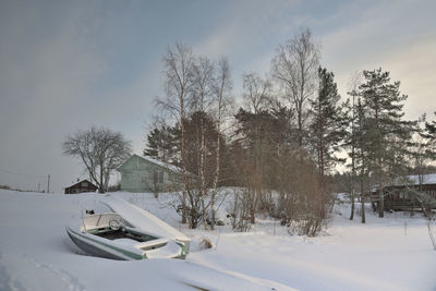 Bare trees on snow covered land against sky