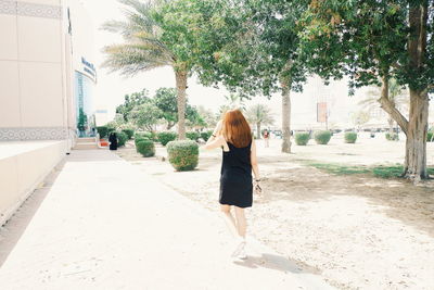 Rear view of woman walking on road in city