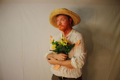 Man with bouquet standing against curtain