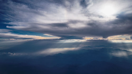 Low angle view of sunlight streaming through clouds