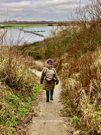 Rear view of man walking on footpath