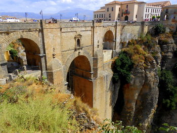 Arch bridge over buildings against sky