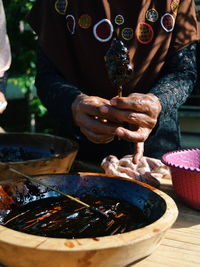 Midsection of man holding food on table while standing outdoors