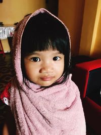 Portrait of cute girl wearing towel on head while standing at home