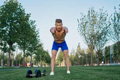 Full length of shirtless man exercising in park