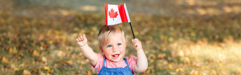 Caucasian baby toddler girl waving canadian flag in park outdoor.  web banner header.