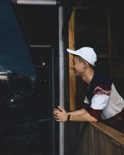 Side view of young man standing on balcony at night