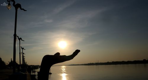 Silhouette of cupped hand against sky during sunset