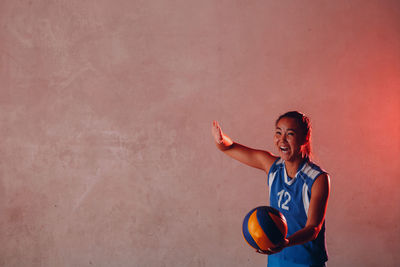 Smiling young woman standing against wall