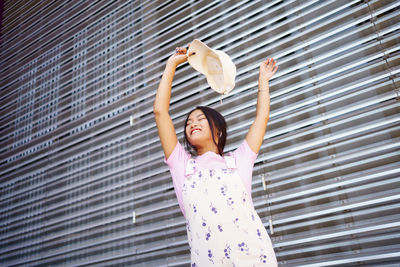 Full length of woman standing against wall