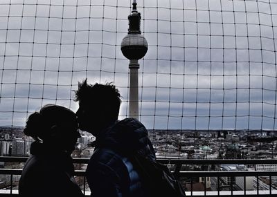 Man kissing girlfriend on forehead by fernsehturm in city